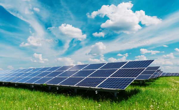 Solar panel on blue sky background. Green grass and cloudy sky. Alternative energy concept